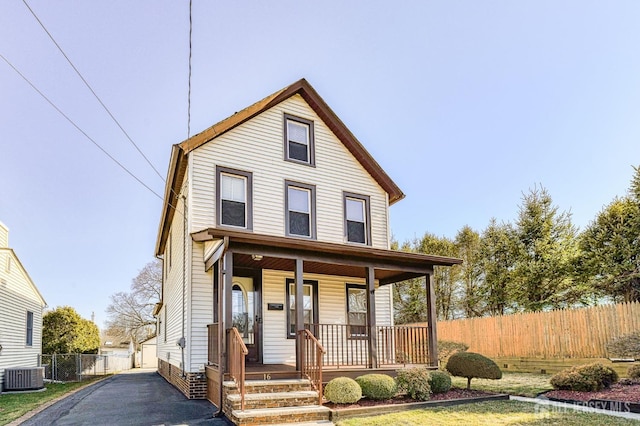 view of front of home featuring central AC unit, a porch, and fence