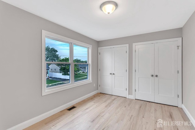 64 2nd Ave, Port Reading, NJ 07064 - unfurnished bedroom featuring two closets, light wood-type flooring, and baseboards