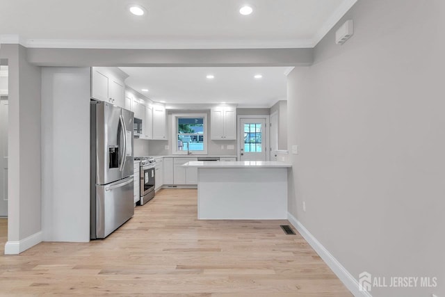 64 2nd Ave, Port Reading, NJ 07064 - kitchen with appliances with stainless steel finishes, a peninsula, ornamental molding, light countertops, and white cabinets