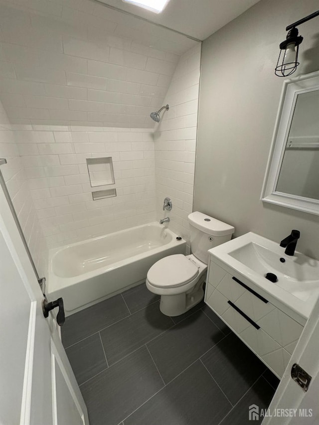 full bathroom featuring tile patterned flooring, tiled shower / bath combo, toilet, and vanity