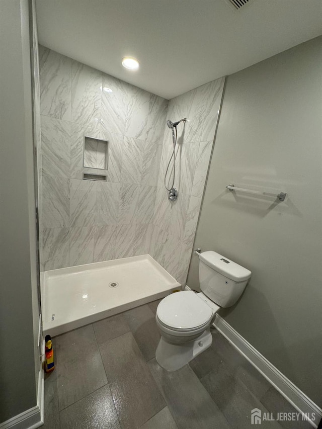 bathroom with tiled shower and toilet