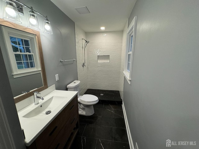 bathroom with vanity, toilet, and a tile shower