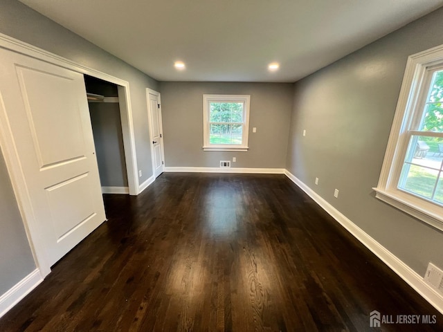 unfurnished bedroom featuring a closet and dark wood-type flooring