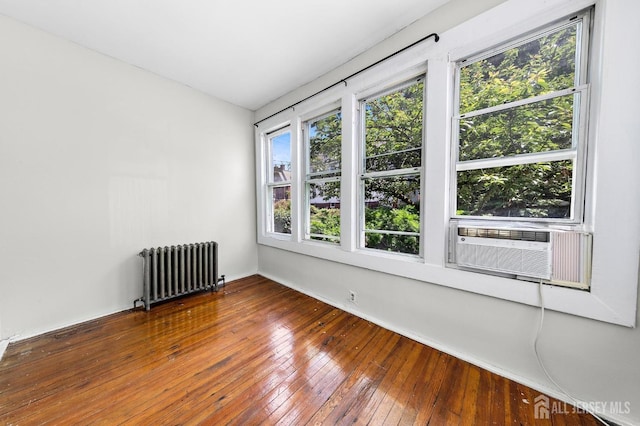 empty room with hardwood / wood-style floors, cooling unit, and radiator