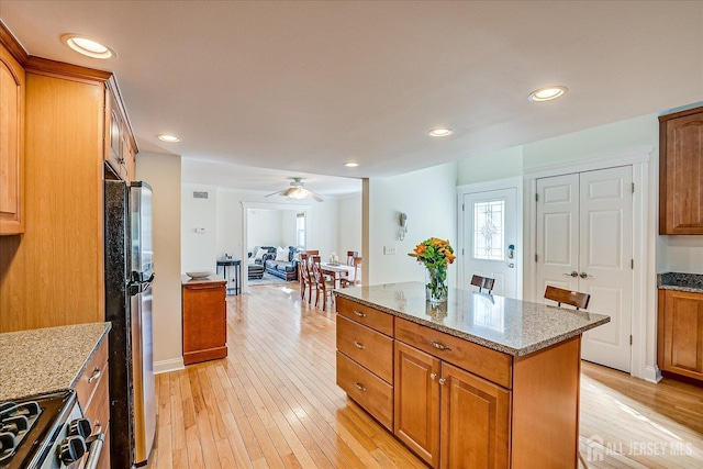 kitchen featuring light wood-style flooring, freestanding refrigerator, and brown cabinets