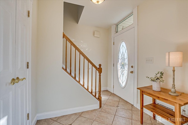 foyer with stairs, light tile patterned floors, and baseboards