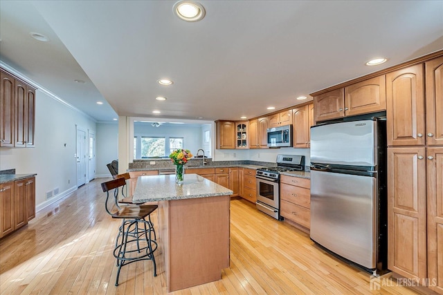 kitchen with a kitchen island, light wood-style flooring, recessed lighting, stainless steel appliances, and a kitchen breakfast bar