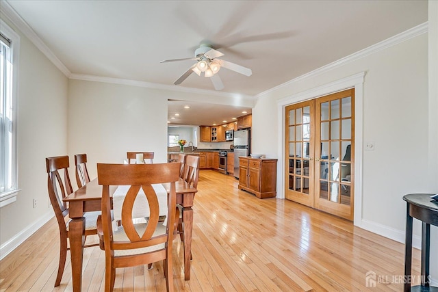 dining area featuring light wood-type flooring, baseboards, and crown molding