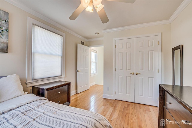 bedroom with a ceiling fan, baseboards, ornamental molding, light wood-style floors, and a closet