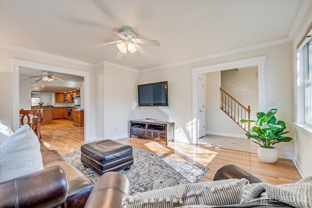 living area featuring stairway, light wood-type flooring, a wealth of natural light, and ornamental molding