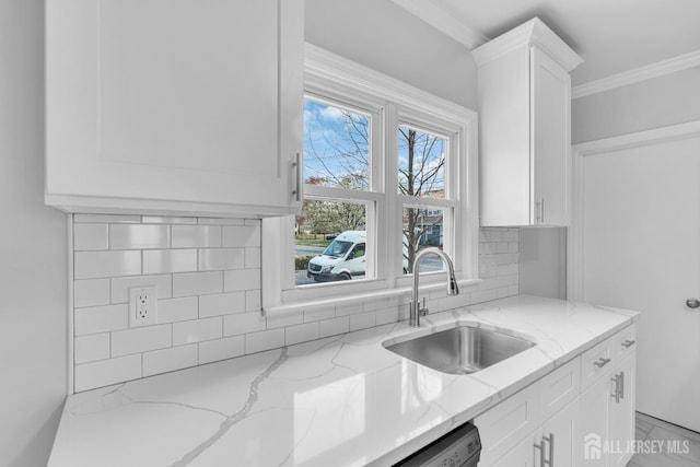 kitchen with a sink, tasteful backsplash, white cabinetry, light stone counters, and ornamental molding