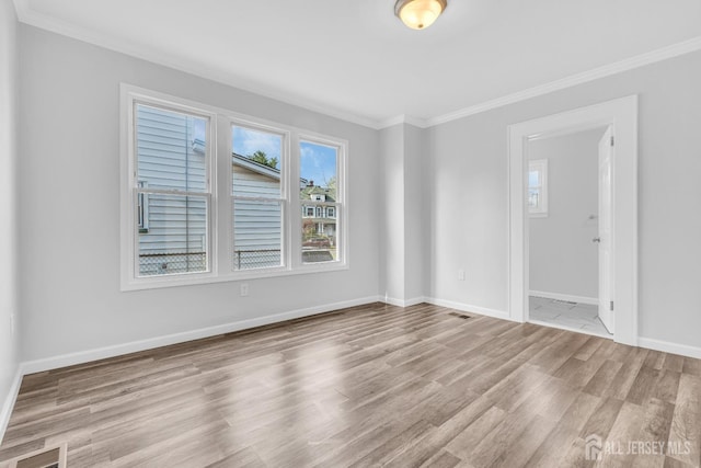 unfurnished room featuring ornamental molding, wood finished floors, and baseboards