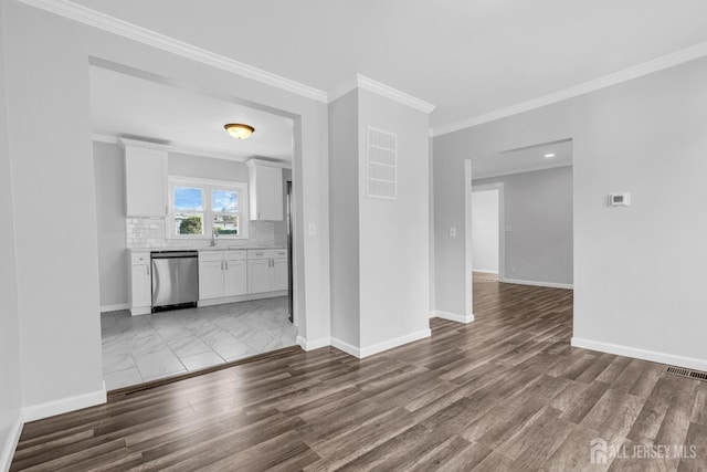 unfurnished living room featuring baseboards, ornamental molding, wood finished floors, and a sink