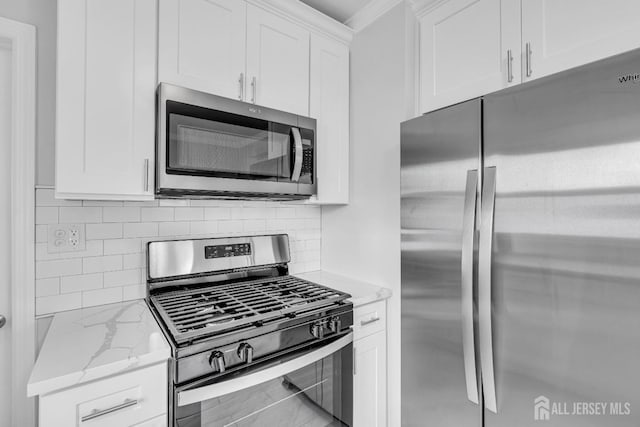 kitchen featuring appliances with stainless steel finishes, light stone counters, white cabinets, and backsplash