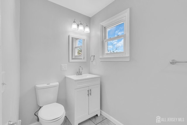 bathroom with marble look tiles, baseboards, toilet, and vanity