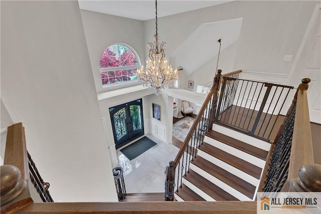 foyer with french doors, a towering ceiling, and an inviting chandelier