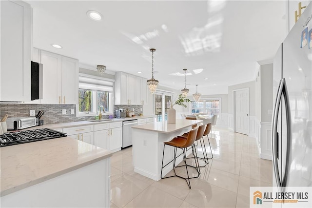 kitchen featuring a center island, white cabinetry, stainless steel appliances, and a wealth of natural light