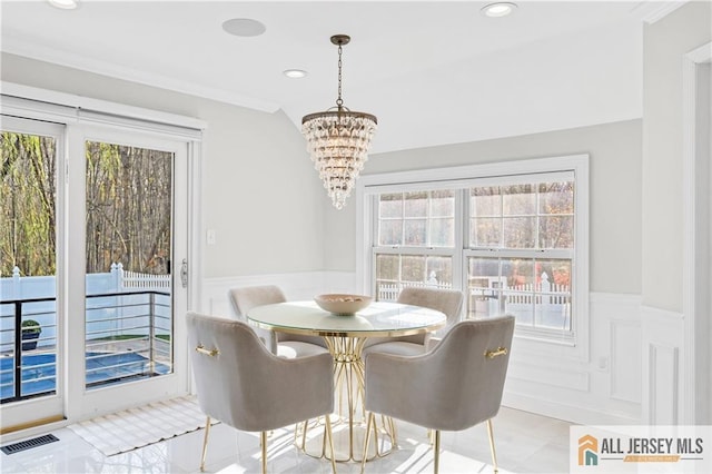 tiled dining room with crown molding and an inviting chandelier