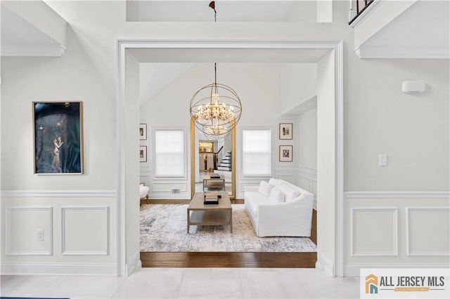 living room featuring wood-type flooring, an inviting chandelier, and ornamental molding