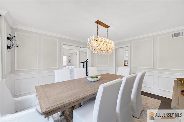 dining space with a chandelier, wood-type flooring, and crown molding