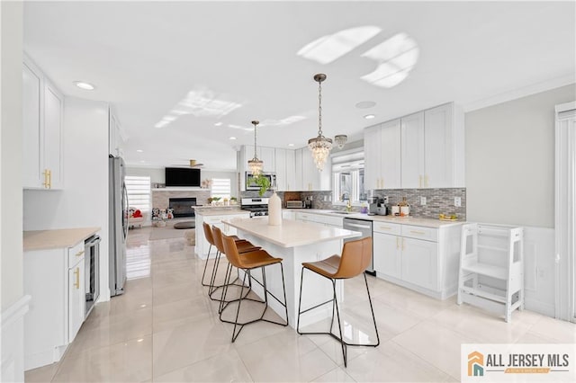 kitchen with white cabinets, a center island, backsplash, and stainless steel appliances