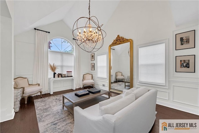 living room featuring dark wood-type flooring, an inviting chandelier, and lofted ceiling