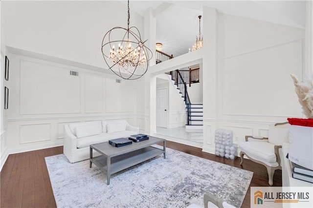 living room featuring high vaulted ceiling, dark hardwood / wood-style floors, and an inviting chandelier