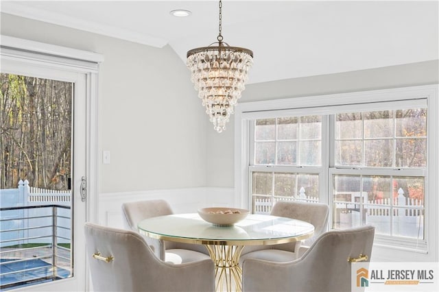 dining space with ornamental molding, a healthy amount of sunlight, and an inviting chandelier