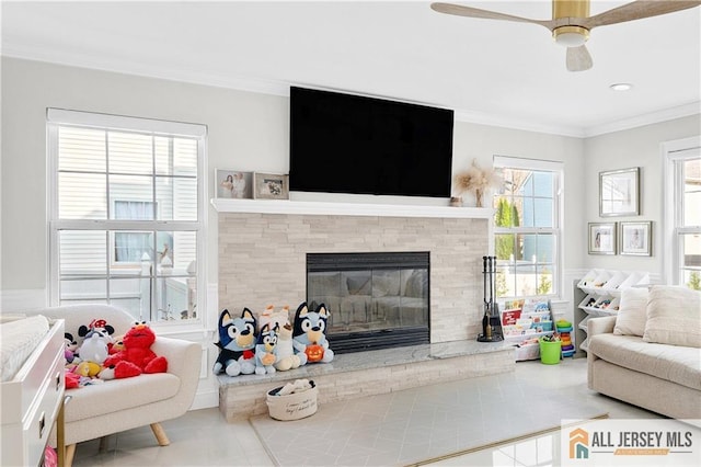 living room featuring tile patterned floors, crown molding, a fireplace, and ceiling fan