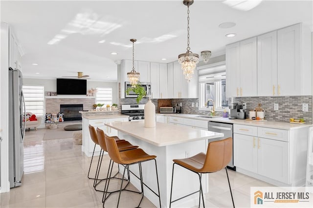 kitchen featuring decorative backsplash, a center island, white cabinets, and stainless steel appliances