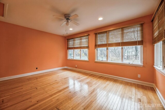 unfurnished room with a wealth of natural light, ceiling fan, and light hardwood / wood-style floors