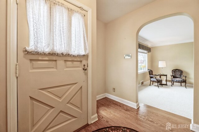 doorway to outside featuring wood-type flooring and ornamental molding