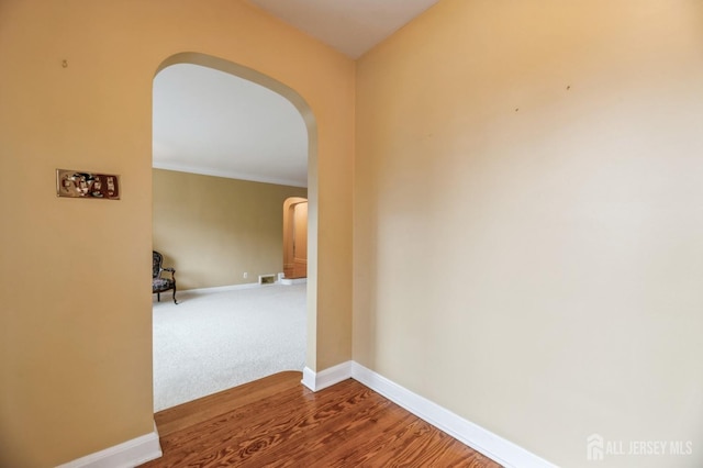 corridor with hardwood / wood-style flooring and ornamental molding