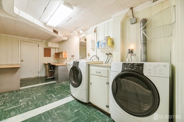 laundry area featuring separate washer and dryer, wood walls, cabinets, and ornamental molding