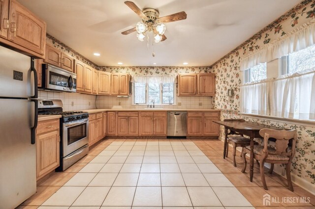 kitchen featuring sink, ceiling fan, decorative backsplash, appliances with stainless steel finishes, and light tile patterned flooring