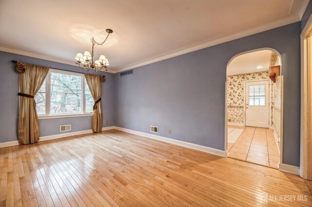 empty room featuring an inviting chandelier, light hardwood / wood-style flooring, and ornamental molding