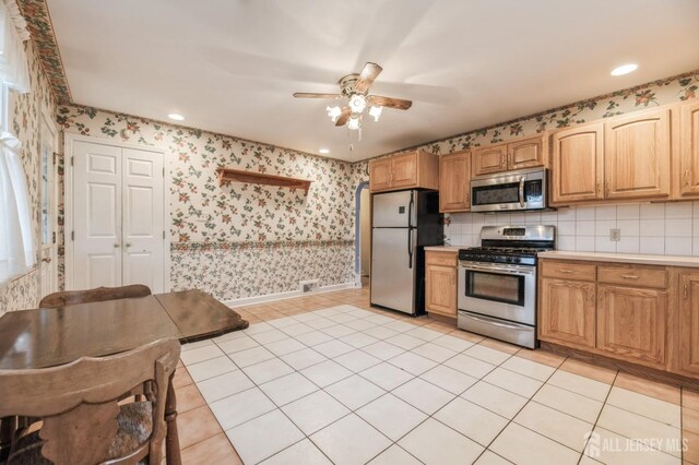 kitchen featuring decorative backsplash, appliances with stainless steel finishes, ceiling fan, and light tile patterned flooring