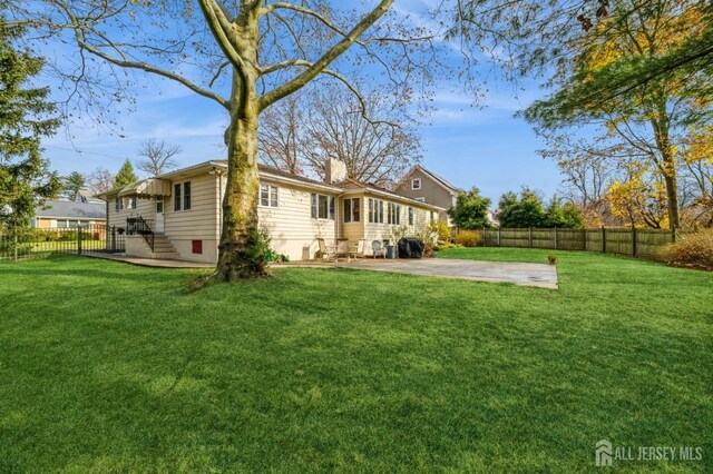 back of house with a lawn and a patio area