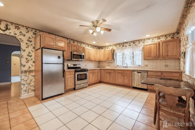 kitchen with tasteful backsplash, stainless steel appliances, ceiling fan, sink, and light tile patterned floors