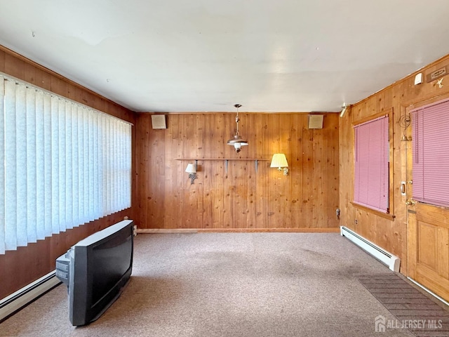 carpeted empty room featuring wood walls and a baseboard heating unit