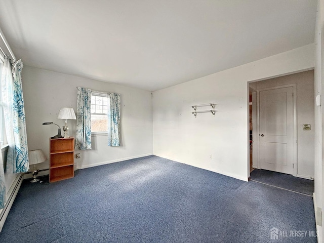 spare room featuring dark carpet and baseboards