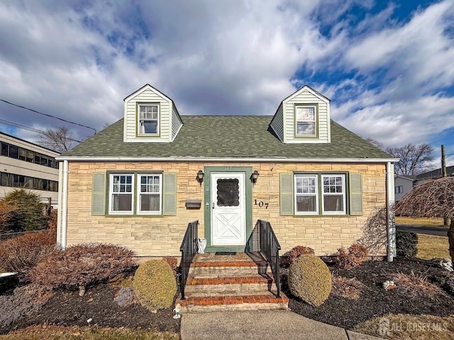 new england style home with stone siding and a shingled roof