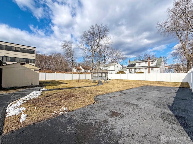 view of yard featuring an outbuilding, a fenced backyard, and a storage unit