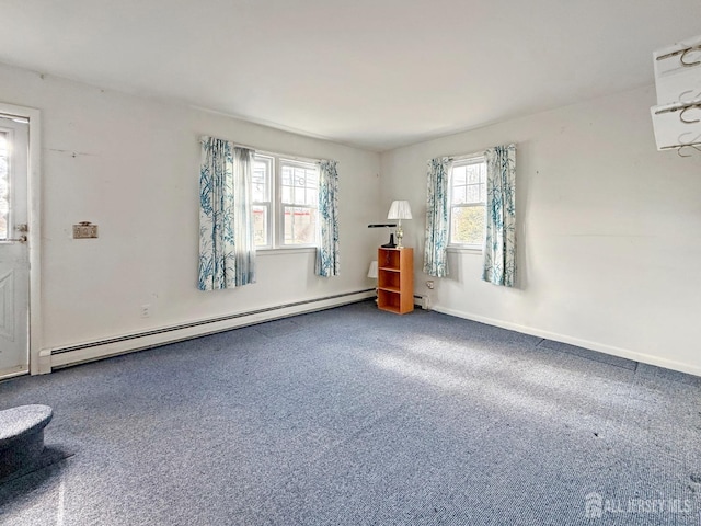 carpeted spare room featuring a baseboard heating unit and baseboards