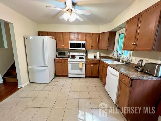 45 Browning Ave, Ewing, NJ 08638 - kitchen featuring white appliances, brown cabinetry, ceiling fan, dark countertops, and light tile patterned floors