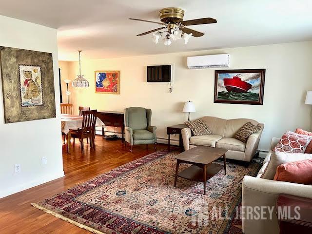 45 Browning Ave, Ewing, NJ 08638 - living area with an AC wall unit, wood finished floors, a ceiling fan, and a baseboard heating unit