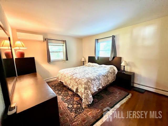 45 Browning Ave, Ewing, NJ 08638 - bedroom featuring a wall mounted air conditioner, baseboard heating, wood finished floors, and multiple windows