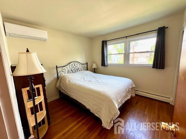 45 Browning Ave, Ewing, NJ 08638 - bedroom with an AC wall unit, baseboard heating, and wood finished floors