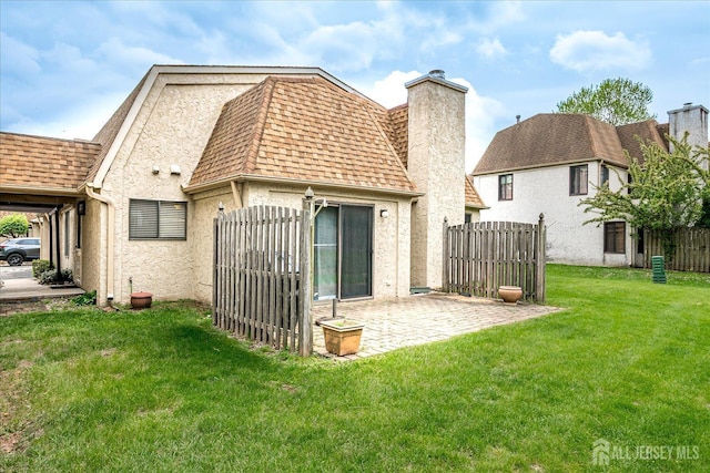 rear view of house with roof with shingles, fence, a yard, and a chimney