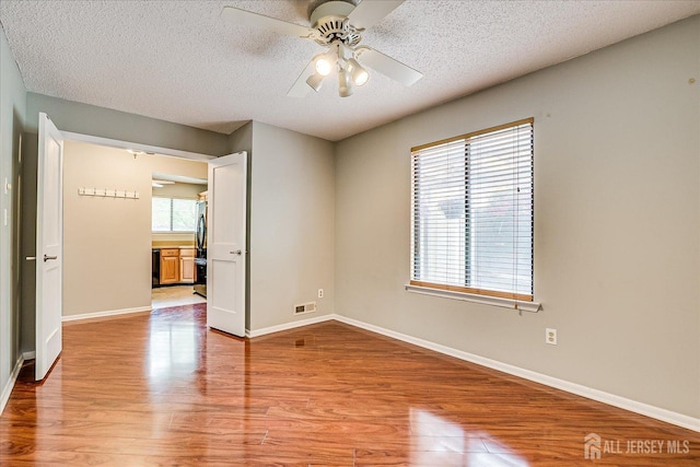 spare room featuring a ceiling fan, a textured ceiling, and light wood-style floors